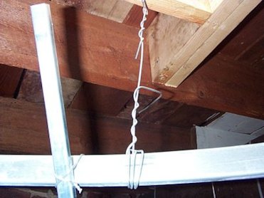 Eye hooks are screwed into the joists. 1-1/2 inch iron is tied with 9 gage hanger wire. There are 4 hanger wires.